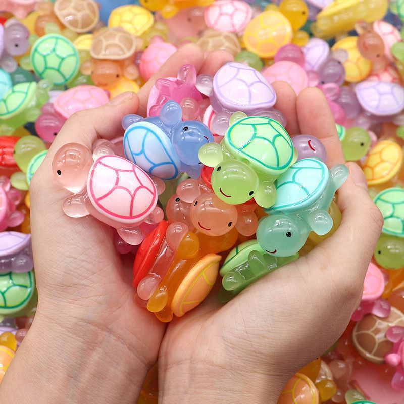 Tortue lumineuse tenue entre les doigts pour montrer sa taille