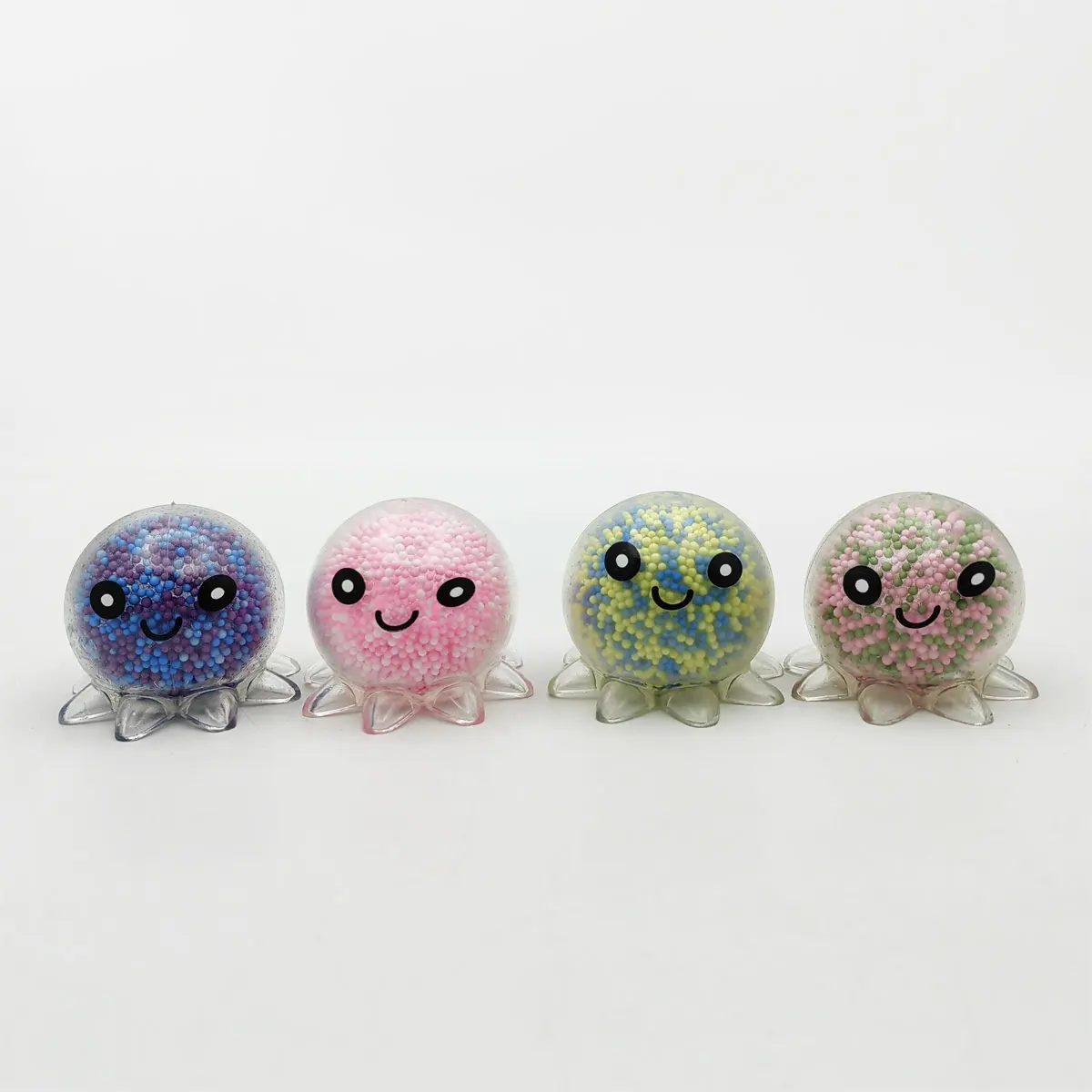 Quatre poulpes anti-stress à billes de mousse posés sur des socles blancs