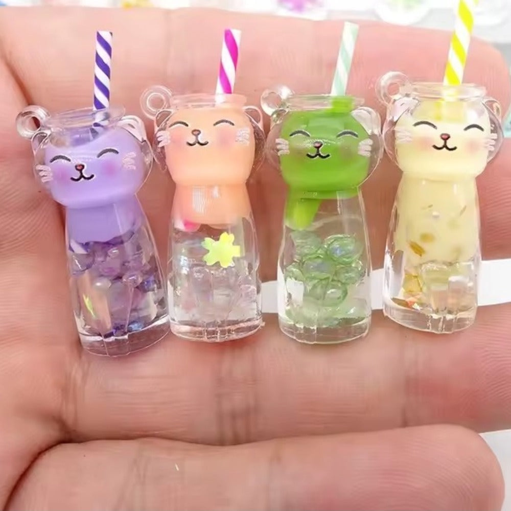 Quatre porte-clés chat boba tenus dans une main, violet, orange, vert et jaune, pour montrer leur petite taille