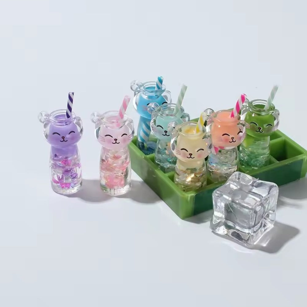 Porte-clés chat boba disposés dans un bac à glaçons vert à côté d'un cube de glace