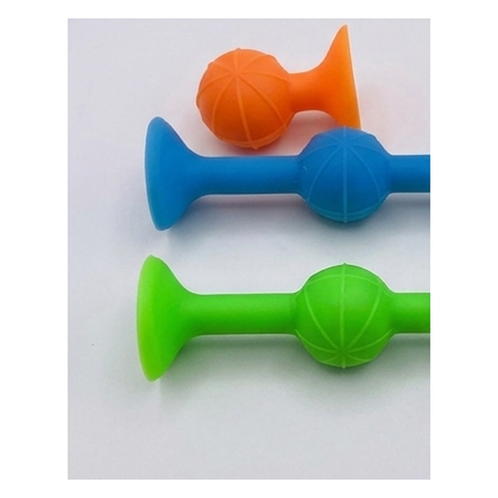 Trois fléchettes ventouses souples orange, bleue et verte posées sur une surface claire