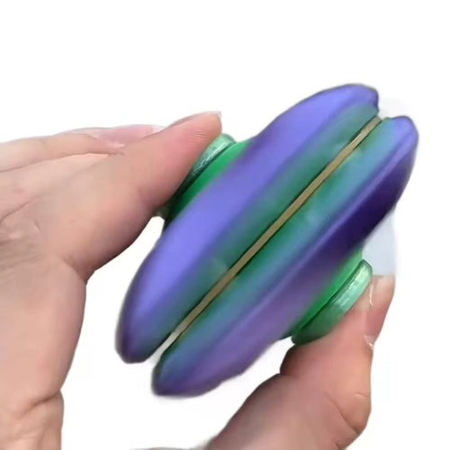 Balle toupie violette et verte aplatie en toupie entre deux mains